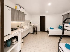 a room with a bed and a kitchen with a sink at Anluka House mono araña in Puerto Jiménez
