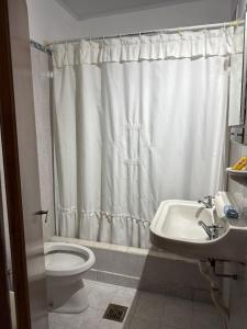 a bathroom with a white shower curtain and a toilet and sink at Alvarado in San Pedro