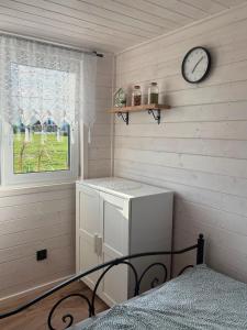 a bedroom with a clock on the wall and a bed at Domek Chabrowy Gowidlino in Gowidlino