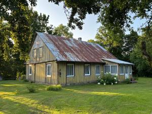 an old house with a rusty tin roof on a yard at Stovyklavietė Dauba in Šyliai