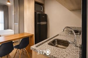 a kitchen with a sink and a refrigerator at Studio com Garagem e Acessibilidade | Granja Viana in Taboão da Serra