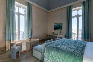 a bedroom with a tub and a bed and a bed and window at EGEO - Ortigia in Syracuse