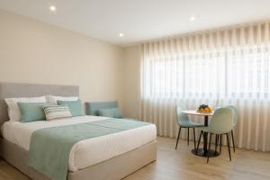 a bedroom with a bed and a table and chairs at Calvário Suites III in Chaves