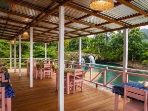 a deck with tables and chairs and a waterfall in the background at Cascata- Pousada Encanto Do Mar in Santa Irene