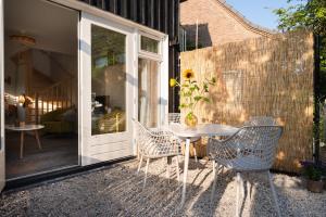 a patio with a table and chairs and a glass door at Kortbie Zee in Biggekerke