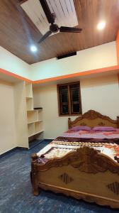 a bedroom with a large wooden bed with a ceiling fan at Durga Devi Home stay in Hospet