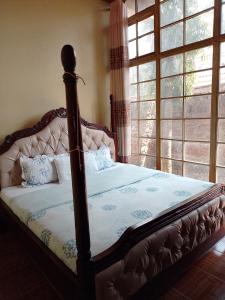 a bed in a bedroom with a large window at Oundo LVHAR in Busia