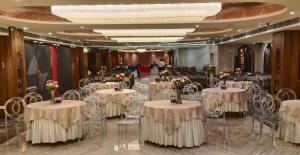 a banquet hall with white tables and chairs at Hotel CP Palace in Patna