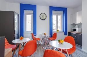 a kitchen with two tables and orange chairs at Sky Hostel in Zadar