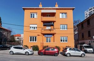 three cars parked in front of a orange building at Sky Hostel in Zadar