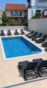 a swimming pool with lounge chairs next to a building at M2 Apartmani in Trebinje