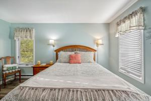 a bedroom with a large bed and two windows at Herons Rest -- Riverfront, Fire Pit, All seasons Porch, Grill, Games, Fishing, Deck, Wifi, River view in Great Cacapon