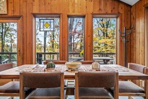 a dining room with a table and chairs and windows at Haven Home - Deck, Grill, Hiking, Pool Access, Games, Community Playground and Tennis Courts in Berkeley Springs