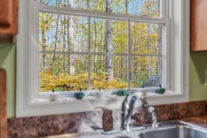 a kitchen sink with a window looking out at trees at Trails End River Retreat - Riverside in Berkeley Springs +87 photos