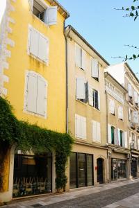 a yellow building with white shuttered windows on a street at Le Jardin de Freya - Balnéo - Centre historique in Auch