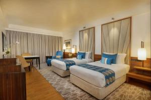 a hotel room with two beds and a desk at Hotel DSR Krone New Delhi in New Delhi
