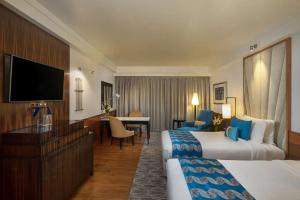 a hotel room with two beds and a flat screen tv at Hotel DSR Krone New Delhi in New Delhi