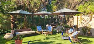 a garden with two umbrellas and chairs on the grass at Tuinvrede Guesthouse in Welgemoed
