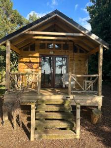 a log cabin with a porch and a swing at Pinetree Lodge, Cotswolds in Mickleton