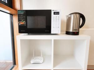 a microwave sitting on top of a white shelf at Beacon Guest Rooms Sandyford in Sandyford