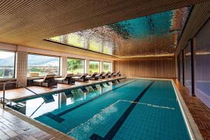 a large swimming pool with chairs and a large window at Kobaldhof in Ramsau am Dachstein