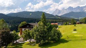 a house in a field with mountains in the background at Kobaldhof in Ramsau am Dachstein