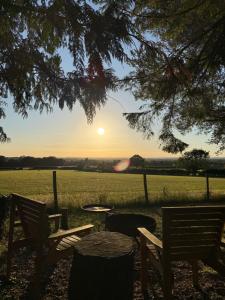 a sunset over a field with a table and chairs at Pinetree Lodge, Cotswolds in Mickleton +9 photos