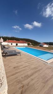 a large swimming pool with a wooden deck and a blue at Casinha de Roliça in Roliça