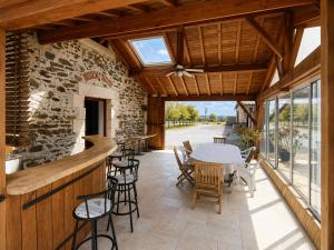 a patio with a table and chairs and a stone wall at Domaine de Beau Site in Peyrat-de-Bellac