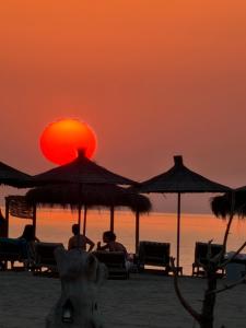 people sitting under umbrellas on the beach at sunset at White Houses Complex in Fier