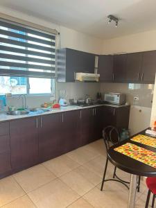 a kitchen with dark brown cabinets and a table and a tableablish at Departamento impecable en Tonsupa, Conjunto Vacacional Salaverry VI in Tonsupa