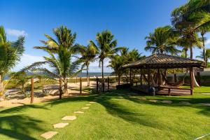 a park with a gazebo and palm trees and the ocean at Areias de Itacimirim in Itacimirim