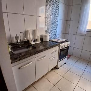 a small kitchen with a sink and a stove at Apartamento Sossego! in Uberaba