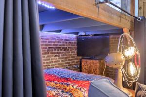 a room with a bed and a tv and a brick wall at Sweet Lancaster Apt. A in Lancaster
