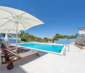 a swimming pool with lounge chairs and an umbrella at Hippothoi Sea View Maisonette in Mesochórion