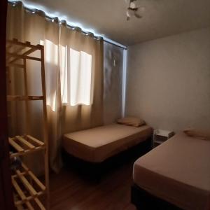 a small bedroom with two beds and a window at Apartamento Serenidade! in Uberaba
