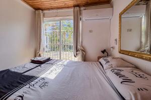 a bedroom with a bed with a mirror and a window at Bright 2 Bedroom, Private Garden in Herzliya