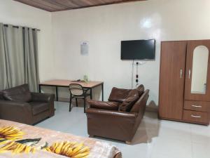 a living room with two chairs and a television on the wall at Royal Irenic Hotel in Madina