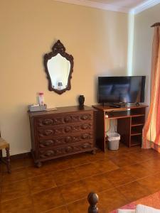 a living room with a television and a dresser with a mirror at Propriedade dos Seixos in Moledo