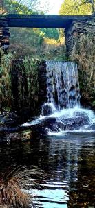 a waterfall under a bridge over a river at Malhada Do Rei Mountain House in Pampilhosa da Serra