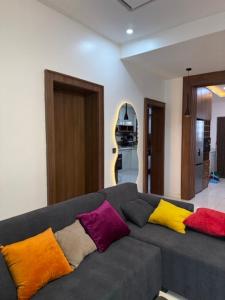 a living room with a gray couch with colorful pillows at 2bedroom Harmony Apartment in Abuja