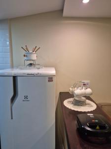 a kitchen with a white refrigerator and a phone on a table at Recanto de Itaipava - casa com forno de pizza a lenha, churrasqueira, pet friendly, equipada para até 6 pessoas, em meio à Natureza e próxima ao centro do bairro in Araras Petropolis +24 photos