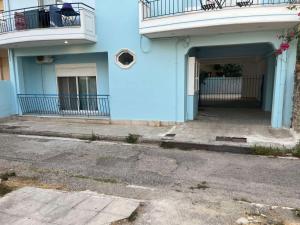 a blue building with a balcony and a parking lot at Efie's cozy home in Missolonghi