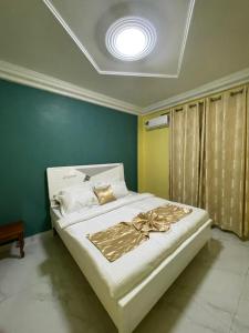 a bedroom with a white bed with a ceiling at Suite premium in Douala
