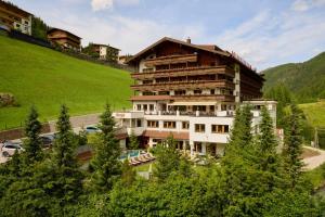 a large building on top of a hill with trees at Hotel Alpenhof in Tux