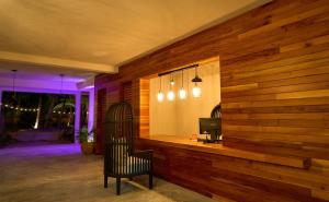 a room with a wooden wall with a chair and a television at Casa del Viento by ÓOL Hotels in Holbox Island