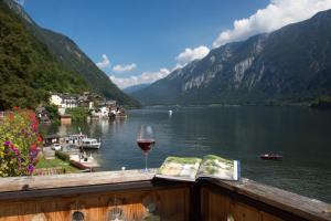 een glas wijn op een balkon met uitzicht op een meer bij Seehotel Grüner Baum in Hallstatt