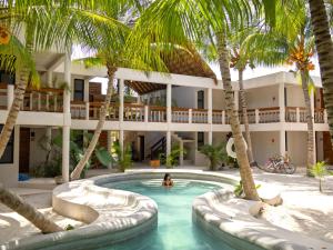 a person in a pool in front of a hotel at Casa del Viento by ÓOL Hotels in Holbox Island