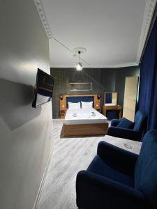 a bedroom with a bed and two blue chairs at Riwaner Hotel in Avcılar