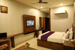 a hotel room with a bed and a tv at Hotel Helios in Zirakpur